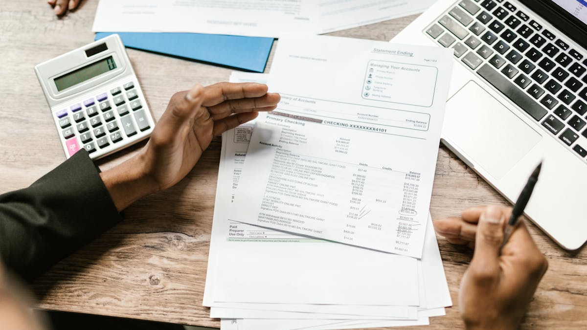 Documents financiers, calculatrice et ordinateur portable sur un bureau — le dossier KYC à constituer pour ouvrir un compte bancaire professionnel à Hong Kong