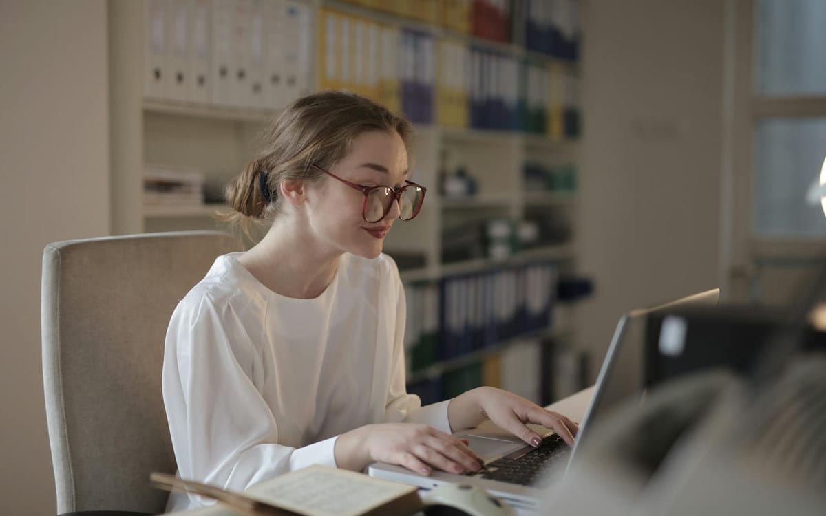 Un professionnel concentré travaillant sur un ordinateur portable dans un bureau moderne et lumineux — un consultant indépendant qui gère des clients internationaux