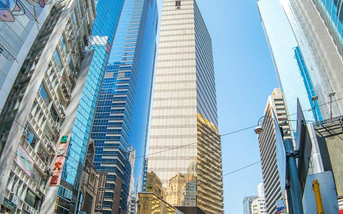 Looking up at gleaming Hong Kong skyscrapers against a clear blue sky — the open, credible business environment a foreign founder taps into
